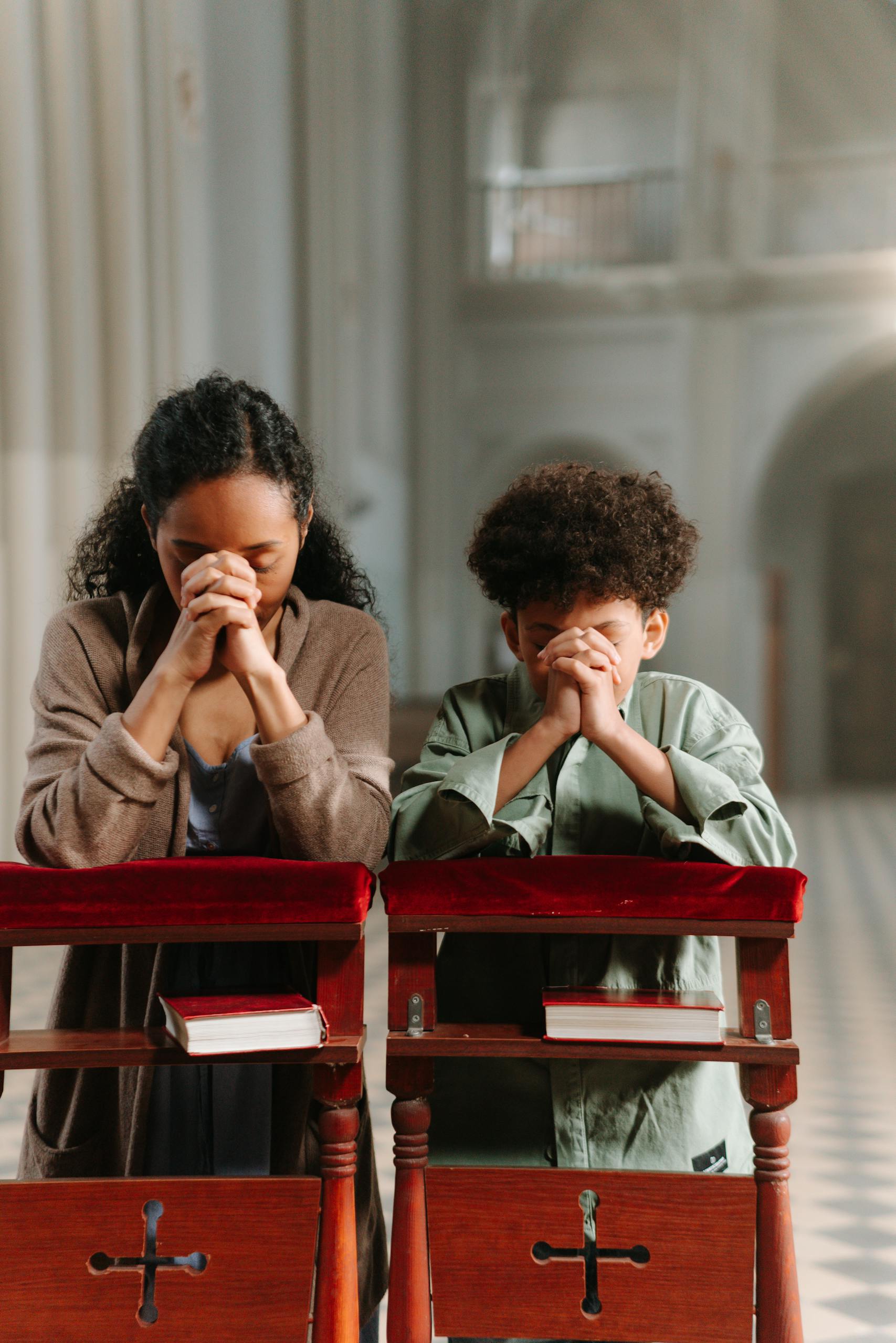 A mother and son pray together in a church, focusing on faith and spirituality.